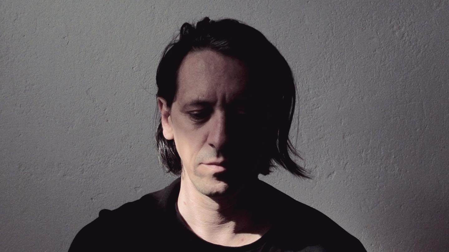 Portrait of Akosch Warga against a textured wall, with his face partly in shadow