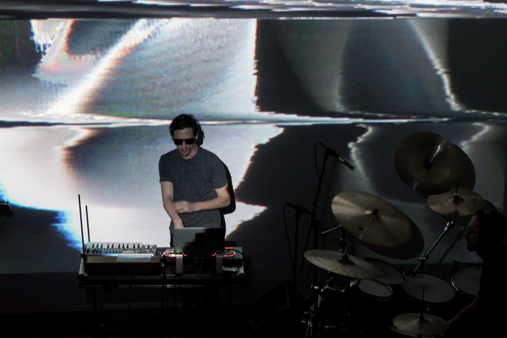 Akosch Warga performing in Berlin, with large projections behind the stage