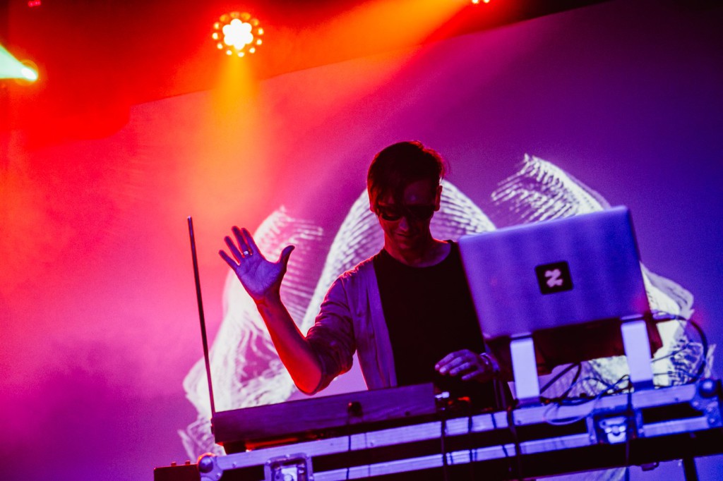 Akosch Warga performing with electronic instruments under red and purple stage lights
