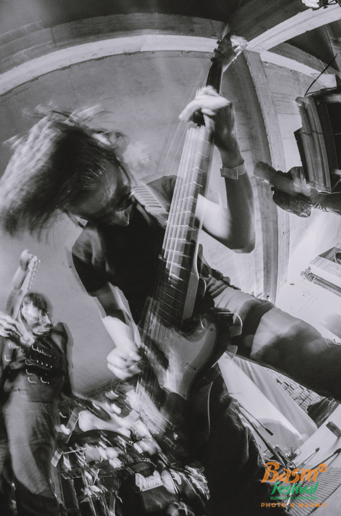Black-and-white photograph of Akosch Warga leaning into a live bass performance